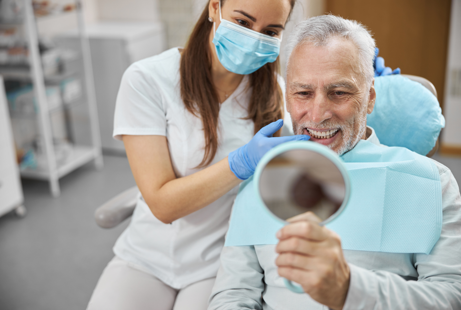 Dentist showing a smiling patient his new smile after dental implant recovery